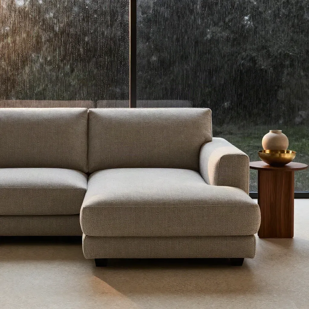 Divano modulare greige con chaise longue, pouf e vaso in ceramica dopo la pioggia